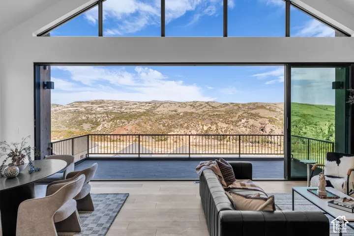 Expansive sliding glass doors open to a spacious balcony with metal railings and a scenic mountain backdrop