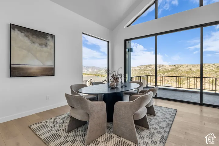 Vaulted ceiling, full-height windows, additional transom windows, wood-finish flooring, and a private balcony with metal railing