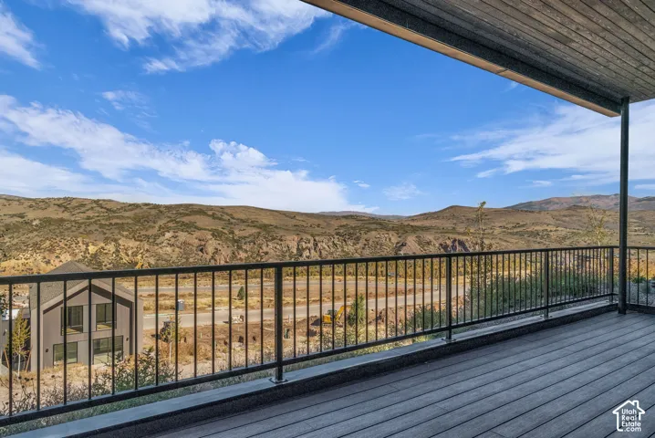 Expansive outdoor deck with composite decking, iron railings, and an overhead wood-finish ceiling, offering mountain scenery
