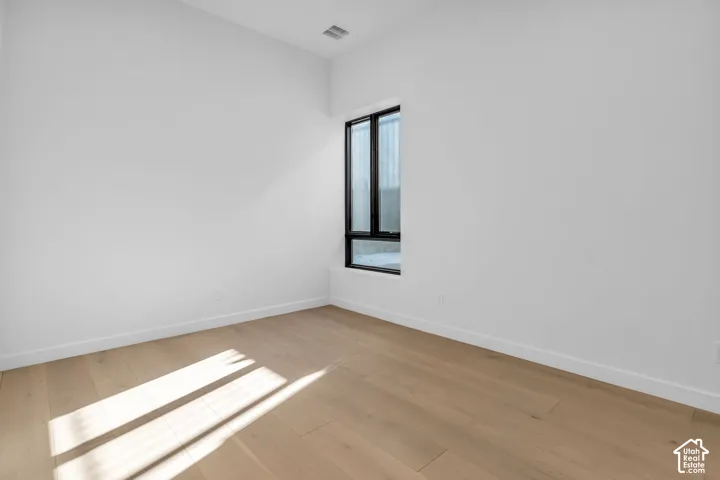 Tall ceilings, light wood-finish flooring, and a black-framed vertical window