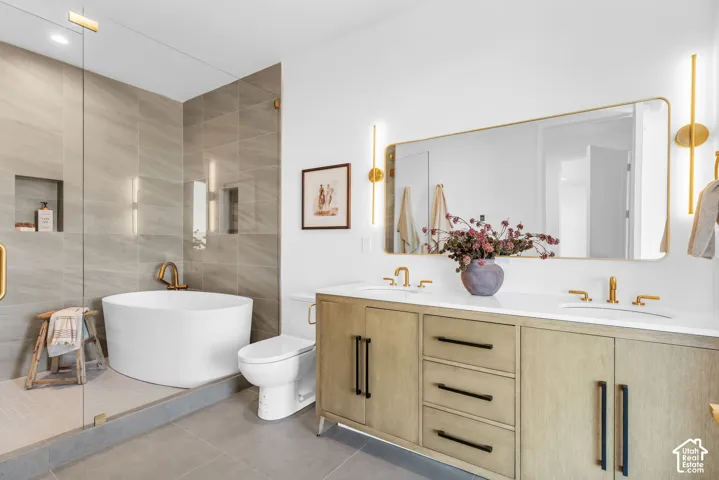 Freestanding soaking tub, large vanity with dual sinks, frameless glass shower enclosure, and tiled shower walls