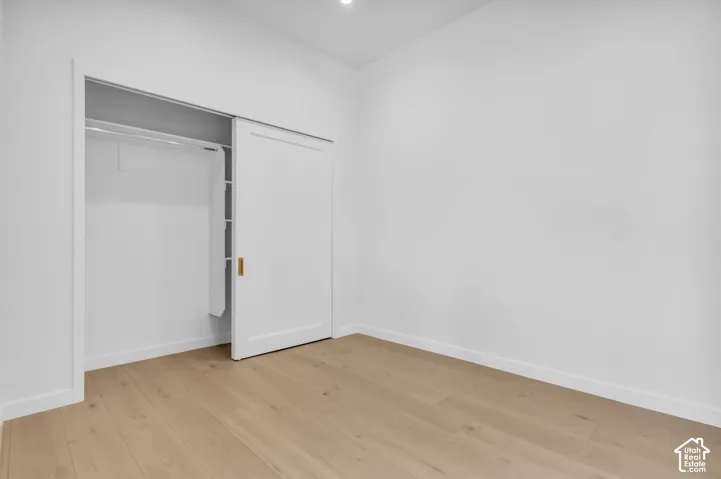 Light wood-finish flooring, white walls, and a sliding door closet with a brass-finish handle