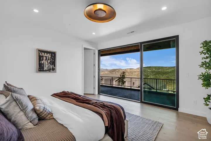 Expansive sliding glass doors, recessed lighting, wood-finish flooring, and a modern ceiling fixture