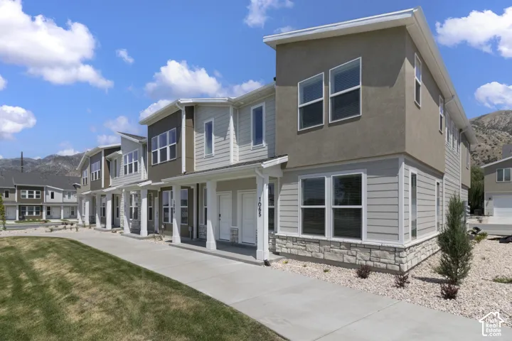 Modern townhome exterior featuring light-colored siding, stone accents, and stucco finish