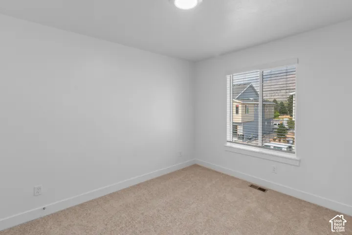 Neutral wall finishes, carpet flooring, a window with blinds, and white trim