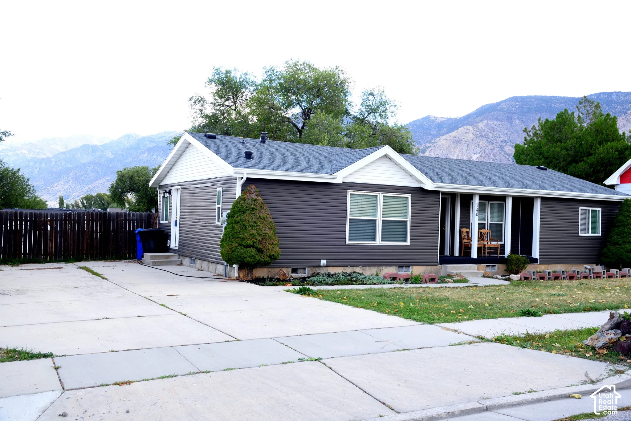 Ranch-style residence featuring a dark gray siding exterior with white trim, a multi-gabled roof, and a covered front porch with white columns