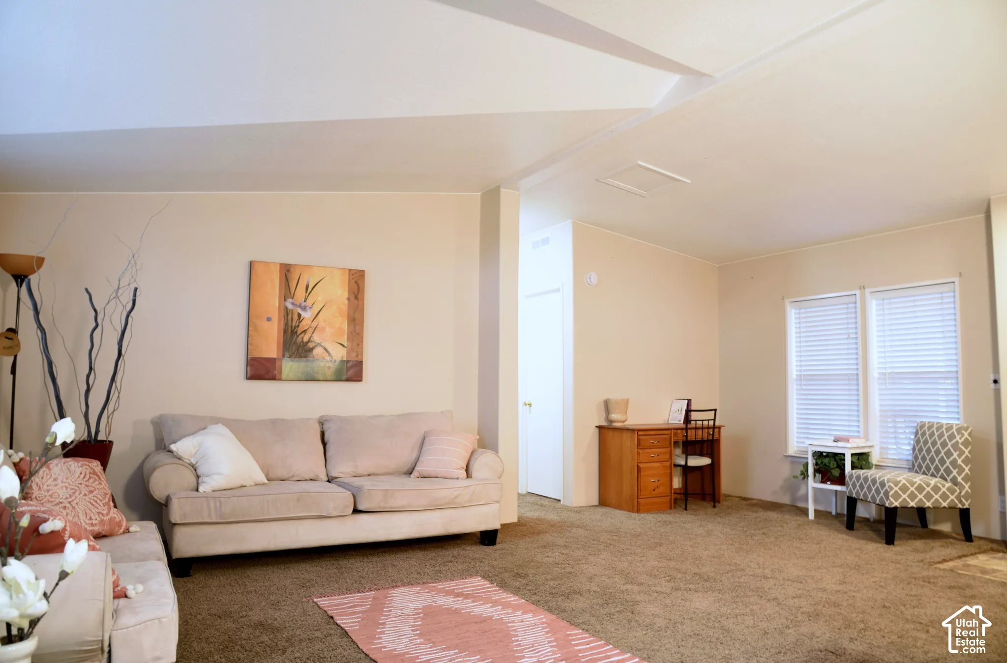 Carpeted living area with light-toned walls and multiple windows