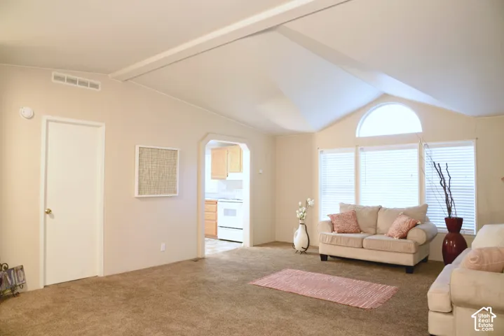 Vaulted ceiling with exposed beam, arched window, and three large windows with blinds