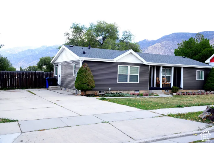 Ranch-style residence featuring a dark gray siding exterior with white trim, a multi-gabled roof, and a covered front porch with white columns