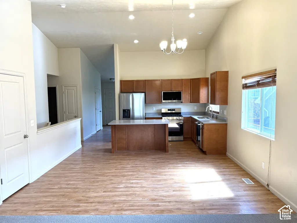 Vaulted ceilings with recessed lighting, wood-finish flooring, and a kitchen featuring wood cabinetry, stainless steel appliances, and an island with a countertop