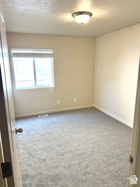 Neutral-toned walls, patterned carpeting, and a window with blinds