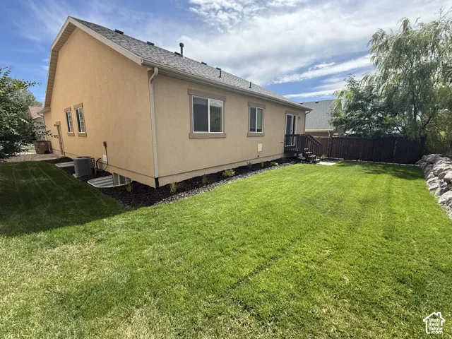 Expansive lawn with a wood fence and natural stone retaining wall