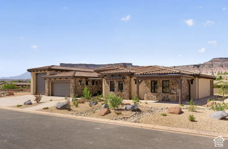 Stone veneer exterior with a tile roof, covered entry, and attached garage