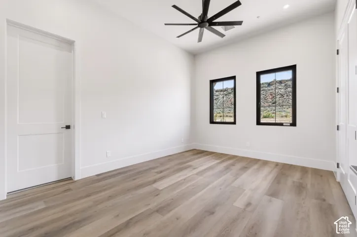 Wood-finish flooring, white paneled doors, black ceiling fan, recessed lighting, and black-framed windows