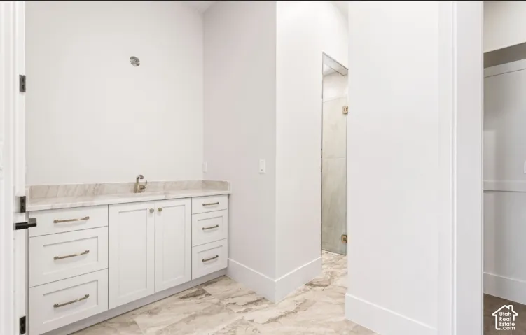 White shaker cabinetry with brushed nickel hardware, marble-finish countertop, and undermount sink