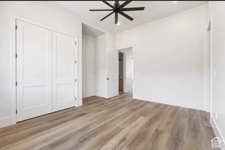 Wood-finish flooring, white paneled doors, recessed lighting, and a ceiling fan
