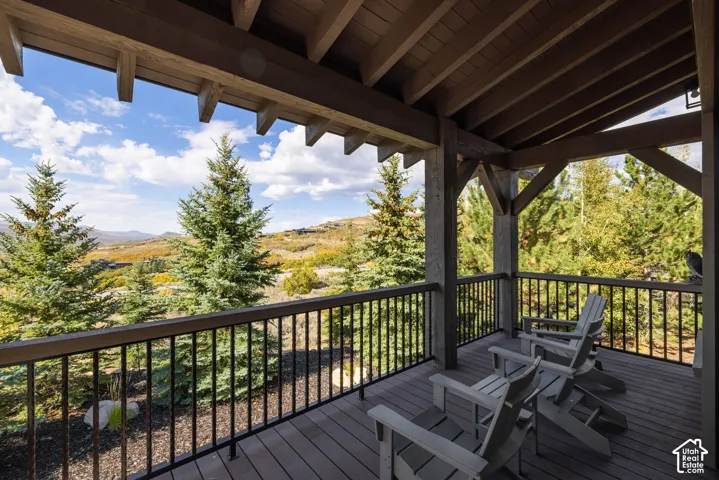 Covered outdoor deck with exposed wood beam ceiling, wood-finish decking, and black metal railings
