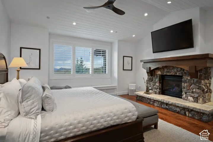 Vaulted tongue and groove ceiling, recessed lighting, wood-finish flooring, stone fireplace with a substantial wood mantel, and a multi-pane window with interior shutters