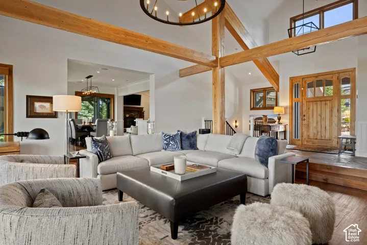 Vaulted ceiling with exposed wood beams, wood-finish flooring, custom wood entry door with glass panels, recessed lighting, and an open-concept layout
