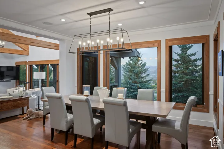 Dining area featuring wood-finish flooring, wood-framed windows, and an exposed timber ceiling beam