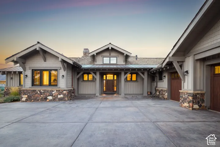 Craftsman-style exterior featuring stone accents, a multi-pane front door, and wood-finish garage doors