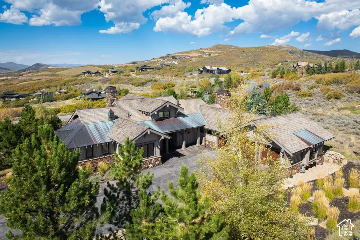 Expansive property featuring a multi-gable roofline, stone and wood siding, multiple garages, and a prominent stone chimney