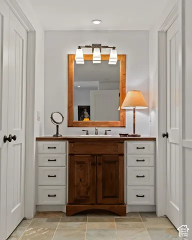Vanity with wood-finish cabinetry, white countertop, and integrated sink