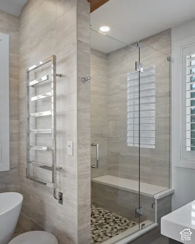 Glass-enclosed shower with pebble-tile flooring, integrated bench seating, and full-height wall tiling