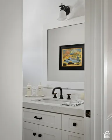 White vanity with Shaker-style cabinetry, a built-in sink, and a matte black faucet