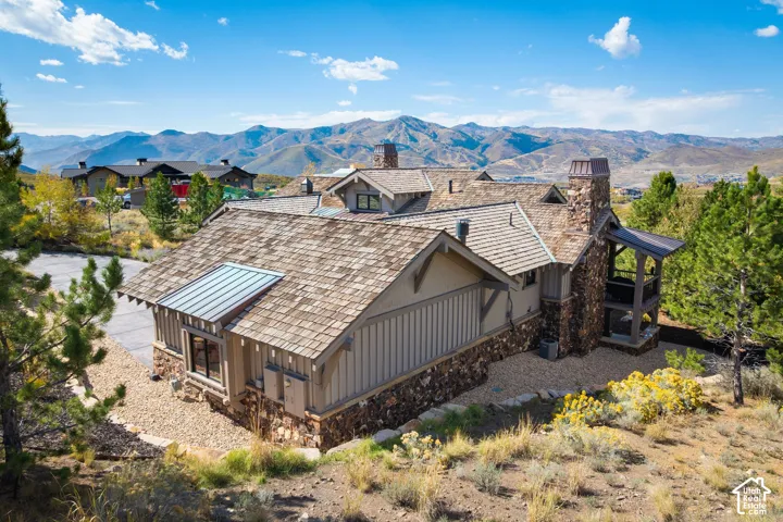 Multi-level property with wood shake roofing, stone veneer siding, and a prominent stone chimney