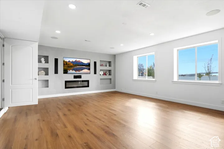 Expansive room featuring wood-finish flooring, recessed lighting, and a built-in electric fireplace