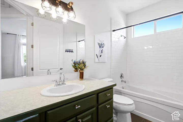 White subway tile shower surround with a built-in tub, overhead transom window, and dark green vanity with an integrated sink and large mirror