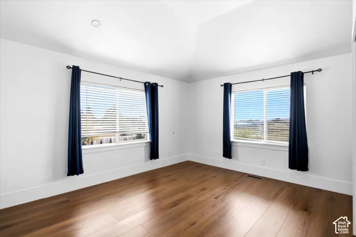 Vaulted ceiling, recessed lighting, wood-finish flooring, and two large windows
