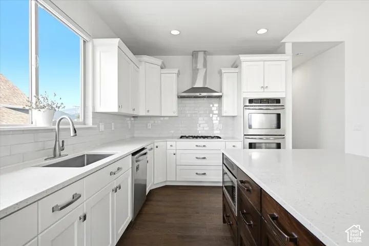 Kitchen featuring white cabinetry, stainless steel appliances, a subway tile backsplash, and a large central island