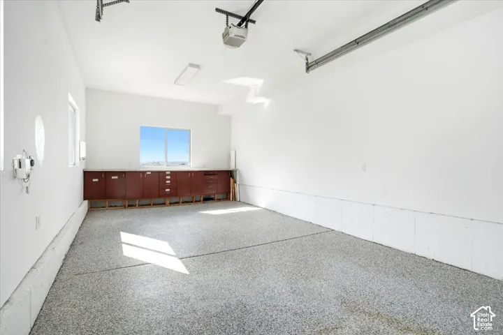Spacious garage with an epoxy-coated floor, built-in cabinetry, and multiple windows