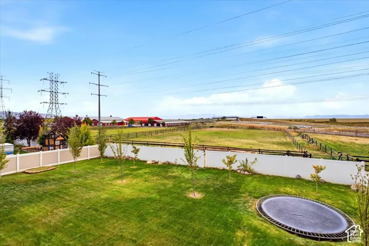 Expansive green lawn with a perimeter fence and scattered young trees