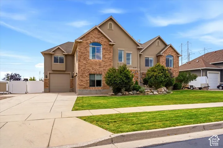 Stucco and brick exterior with arched windows, an attached two-car garage, and a concrete driveway