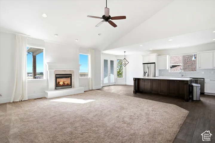 Vaulted ceiling, recessed lighting, built-in fireplace, wood-finish flooring, and white cabinetry