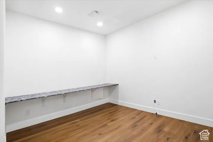Wood-finish flooring, recessed lighting, white walls, and a built-in floating shelf