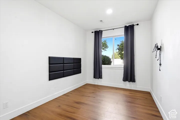 Wood-finish flooring, white walls, recessed lighting, and a prominent window