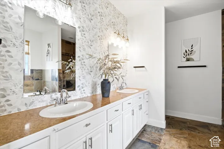 Dual vanity with white cabinetry, brown-toned countertop, and silver-tone faucets