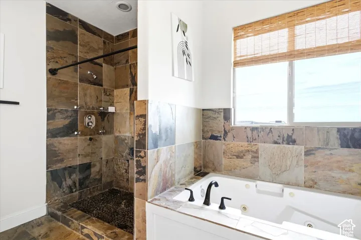 Walk-in shower with natural stone tile and pebble-finish floor