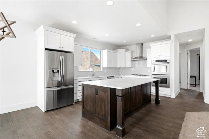 Kitchen featuring a dark wood finish island with a light-toned countertop, white cabinetry, stainless steel appliances, and wood-finish flooring