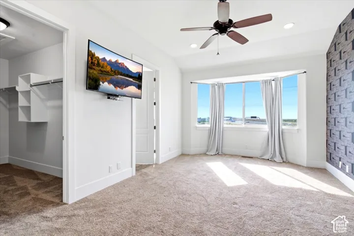 Recessed lighting, ceiling fan, carpeting, bay window, and built-in closet organization system