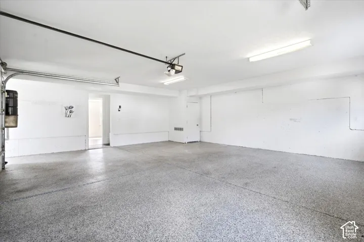 Spacious garage with an epoxy floor, overhead lighting, and white walls