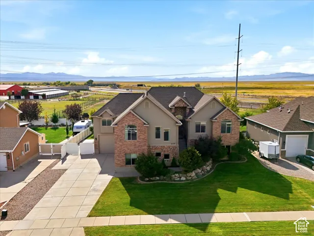 Two-story residence featuring a brick and stucco exterior, a multi-car driveway, and an attached garage