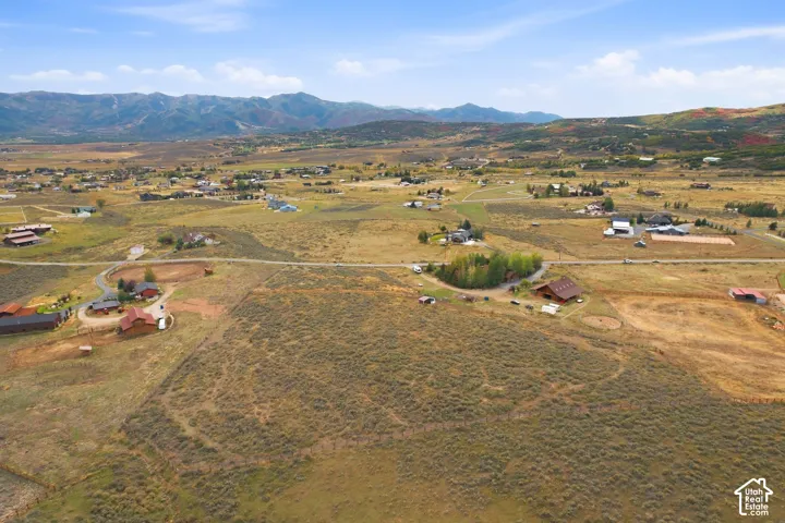 Expansive rural landscape featuring distant mountains and scattered residential structures