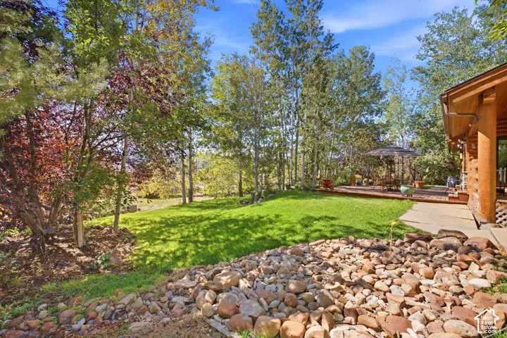 Expansive lawn bordered by mature trees and a rock bed