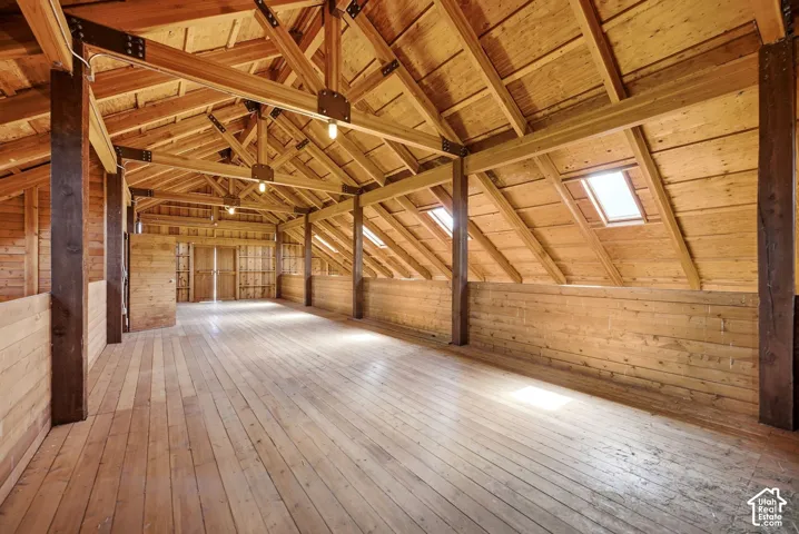 Hay Loft - Spacious open room featuring exposed wood beam construction, skylights, wood-finish flooring, and natural wood plank walls