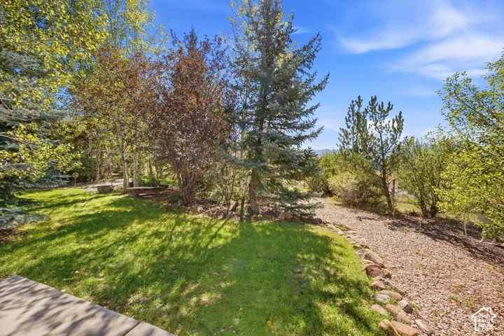 Landscaped grounds featuring a grassy area, mature trees, and a stone-lined gravel path